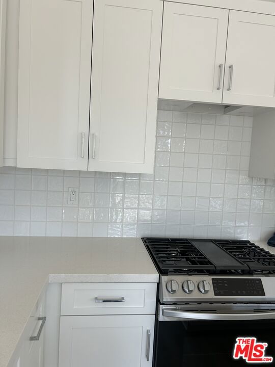 Kitchen with upgraded full backsplash, quartz counters, and white shaker-style cabinets