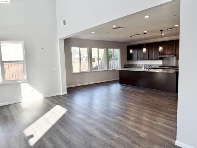 Kitchen with dark brown cabinetry, open floor plan, recessed lighting, dark wood finished floors, and decorative light fixtures