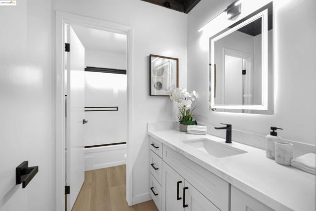 Full bath with vanity, bath / shower combo with glass door, and light wood-type flooring
