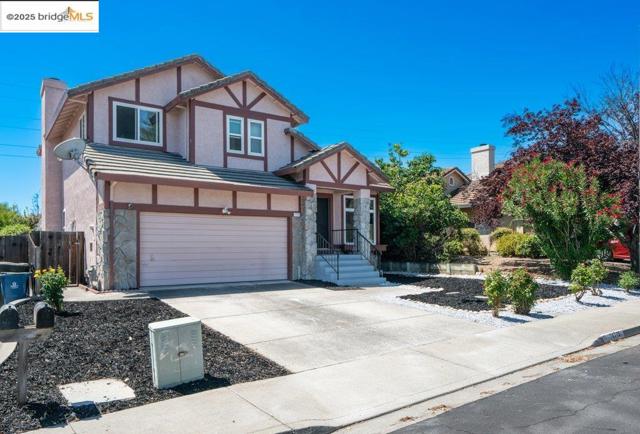 English style home with stone siding, a garage, concrete driveway, and stucco siding