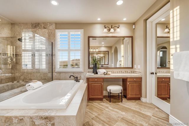 Luxurious dual primary baths with separate spaces. One side features a walk-in shower, vanity, water closet, and walk-in closet. The other offers a large vanity, oversized shower, soaking tub, makeup vanity, water closet, and expansive walk-in closet.