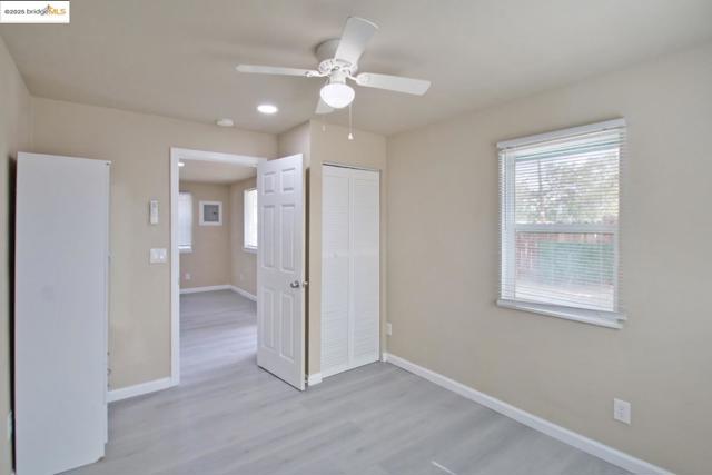 Unfurnished bedroom with light wood-style flooring, ceiling fan, multiple windows, and a closet