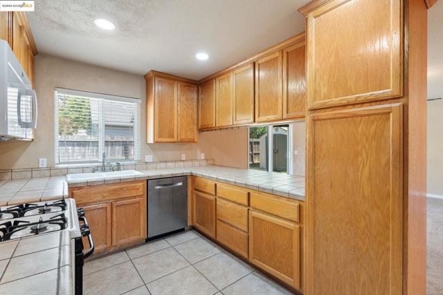 Kitchen featuring white range with gas cooktop, dishwasher, recessed lighting, light tile patterned floors, and a textured ceiling