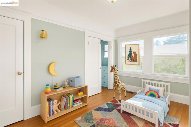 Bedroom with multiple windows, light wood-style floors, and radiator