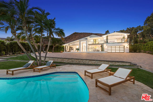 Set on an acre in Malibu, this newly rebuilt contemporary oasis embodies the pinnacle of luxury. Rich in privacy through the gates and up the long driveway awaits this lush paradise. Enter through the 10ft glass door, and experience the highest quality of design and architecture, with top of the line finishes imported from around the globe, from Italian marble floors to designer lighting. Enjoy Malibu living at its finest, with sun drenched rooms, stunning ocean views and disappearing walls of glass that seamlessly blur the lines of indoor outdoor living. The grand open living room boasts vaulted ceilings and flows into the gourmet chef's kitchen complete with top of the line appliances. Off the kitchen is the formal dining room with gorgeous views of the lush grounds and ocean. Two decadent and well appointed ensuite guest bedrooms are downstairs. Up the beautiful marble staircase, enter the magnificent primary suite, replete with vaulted ceilings, fireplace, glass balcony and breathtaking ocean vistas. The resort-like primary bath includes a rain shower, soaking tub, dual vanities and spacious master closet. Outside is an entertainer's paradise with rolling green lawns, mature trees, pool, spa, gazebo, barbecue, fountain, koi pond and 180-bottle vineyard. Located across from world famous Broad Beach, and just past Trancas, enjoy all of the best beaches, hiking trails, shops and restaurants that Malibu has to offer.