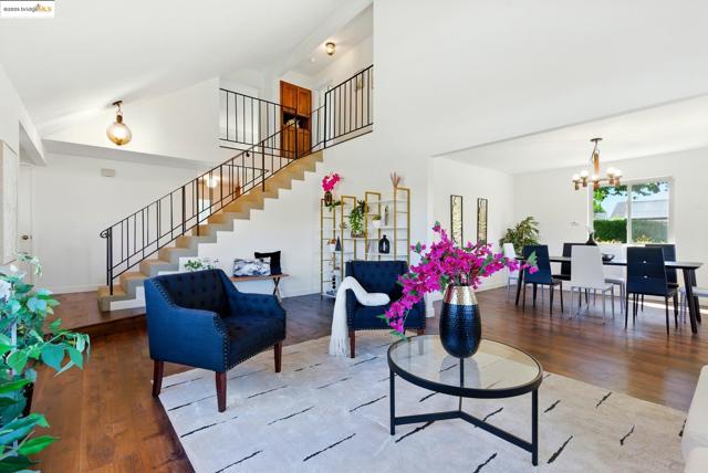 Living room featuring stairway, wood finished floors, a chandelier, and high vaulted ceiling
