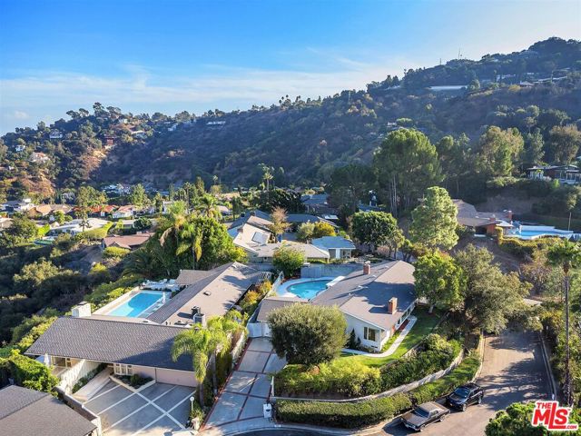 Perched high in the hills of Studio City on a quiet four-residence cul-de-sac, this enchanting modern home sits above the street on a flat lot.  3 BR, 2 BA plus a large den with fireplace.  Flooded with natural light, the house has been updated throughout, with shining hardwood floors and a chef's kitchen equipped with Thermador appliances.  A second fireplace separates living and dining areas. French doors lead to a sun-drenched pool.  In the living room a window seat and huge picture window maximize lovely mountain views.  Updated bathrooms feature elegant tiled floors. The primary bedroom leads to a private deck with striking sunset views.  Newer central heat & A/C and 200-amp electrical panel.  Two-car garage plus ample off-street parking