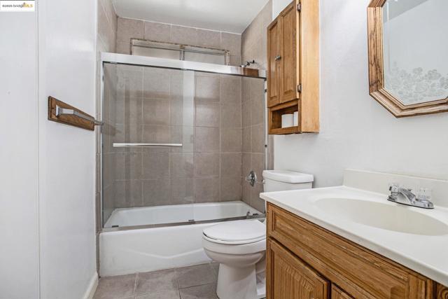 Bathroom featuring combined bath / shower with glass door, vanity, and light tile patterned floors