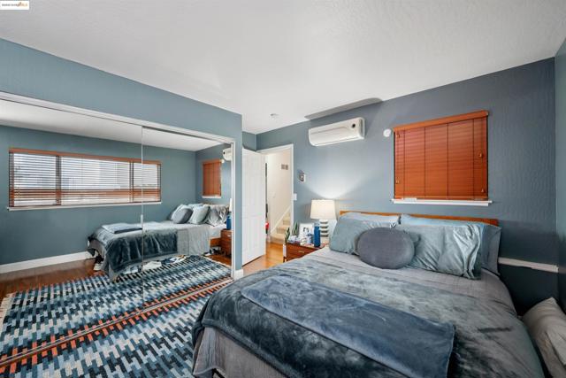 Bedroom featuring a closet, wood finished floors, and an AC wall unit