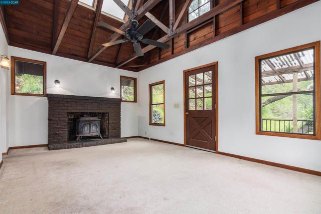 Great room with cast iron, wood burning stove insert in fireplace & beamed ceilings