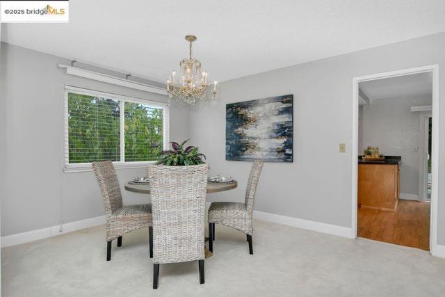 Carpeted dining room featuring baseboards and a chandelier