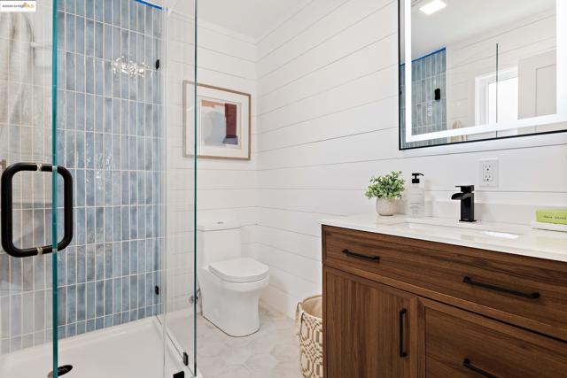 Full bathroom with vanity, a stall shower, light tile patterned floors, and wooden walls