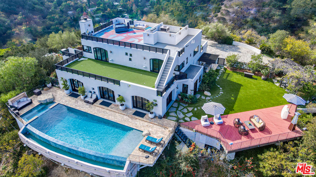 Seeking the ultimate Beverly Hills sanctuary where you can leave behind the hustle and bustle of everyday life? Look no further than this beautifully crafted secluded estate that provides the perfect blend of luxury and tranquility while being just moments from everything LA has to offer! Enviably set on over an acre atop famed Mulholland Drive, this residence commands spectacular views from an impressive 1,300 ft above sea level. A gated, private driveway leads to the grand 2-story facade. Inside, new luxury flooring and dark wood trim tastefully contrasts crisp white tones. Graceful archways greet you in the generously sized open entertainment areas as you seamlessly transition from one room to another. Multiple French doors in the family room and dining area frame sweeping panoramas of the city, ocean, and Catalina Island. A raised-hearth fireplace with a stacked-stone surround anchors the stylish volume ceilings, warming the living room as you gather.  Shake up your favorite cocktails and head outside to relax by the infinity pool and appreciate the stunning views in absolutely every direction you look. Sleek and sophisticated, the chef's kitchen equips you with top-notch stainless steel appliances, abundant white wood cabinetry, granite countertops, an oversized island, and a breakfast nook with access to the patio. Working from home is even better in your private office overlooking breathtaking views. Admire picturesque sunsets from your well-sized bedrooms, adorned with mirrored closets and French doors that open to the large wraparound balcony. Surpassing all in size, the primary suite has a walk-in closet and an ensuite with a spa-like soaking tub and scenic views. Endless hours of fun and leisure await in your expansive outdoors that offers numerous entertaining decks, a resort-style infinity pool, two putting greens, and a pool cabana. Alfresco dining is bliss under the pergola as you enjoy delicious meals prepared on the built-in BBQ island. On cooler nights, sip a refreshing nightcap as you take a soothing dip in the rooftop spa while watching the sunset views and city lights twinkle below. Other notable features include a large private vineyard, a koi pond in the zen garden, a waterfall, and a professional music studio. The estate vineyard produces private reserve wines with multiple varietals, including Pinot Noir, Sauvignon Blanc and Cabernet. The golf decks are beautifully manicured with 9 holes and white artificial sandpits. Convenience is yours with smart-home technology including a Control4 music system, two Nest-operated HVAC units, app-controlled landscape lighting, home protection system, wireless pool features and a 16-camera CCTV system. Its fabulous location puts you near the world-class shopping, dining, and attractions of the Sunset Strip, West Hollywood, and Beverly Hills. Come grab the rare chance to call this Mulholland Oasis home!