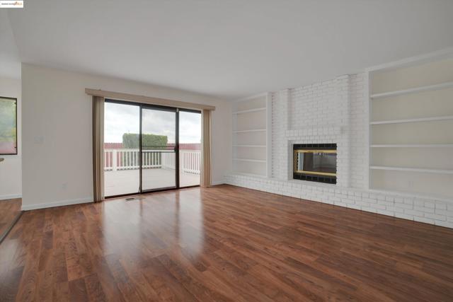 Unfurnished living room featuring dark wood-type flooring, built in features, and a fireplace