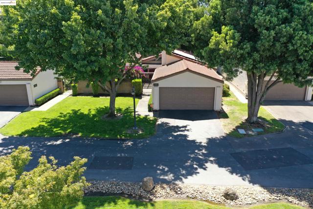 View of front facade with stucco siding, a garage, a front yard, and a tiled roof