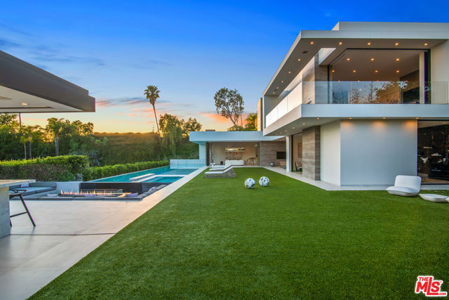 Located on a quiet street off Benedict Canyon and only a few short minutes away from world famous Beverly Hills Hotel and Rodeo Drive, this ultra sleek and museum-quality modern home awaits. Inside a privately gated driveway, a soaring 36' grand entry foyer and fully automated floor-to-ceiling glass walls that disappear at the touch of a button, seamlessly integrate approximately 15,500 sq. ft. of exquisite indoor/outdoor living complete with city and ocean views. A gorgeous chef's kitchen has two custom islands and top of the line appliances. The private primary bedroom retreat has two large closets, dual vanities, and a private balcony. The remaining 5 guest rooms all have generously sized closets and en-suite bathrooms. With a private backyard built for entertaining, a 100-foot infinity pool stretches along with a 12 person spa, outdoor bar, and firepit. Including almost every amenity possible, a large gym and home theater room complete this one-of-a-kind masterpiece.