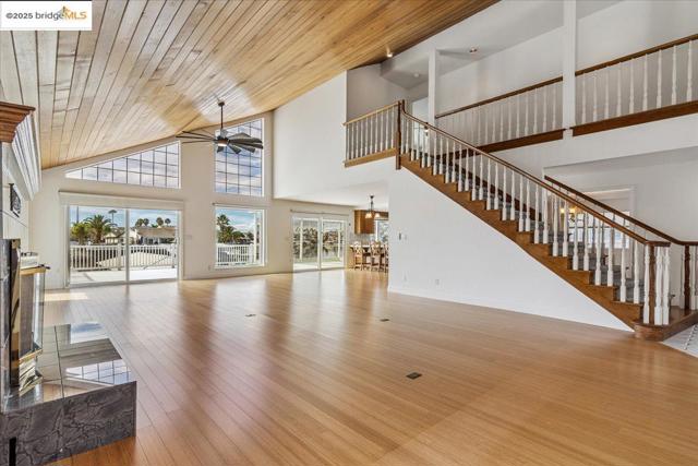 Unfurnished living room with stairs, ceiling fan, hardwood / wood-style floors, wooden ceiling, and high vaulted ceiling