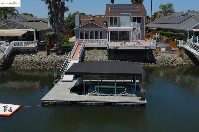 Dock area with a deck with water view, boat lift, and a sunroom