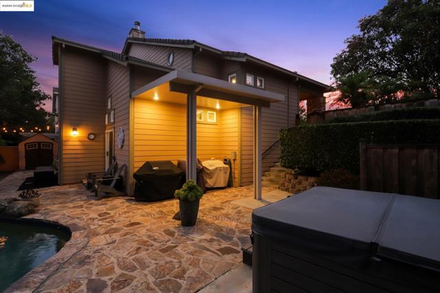 Rear view of house featuring a hot tub, a patio area, a storage unit, a chimney, and an outdoor pool