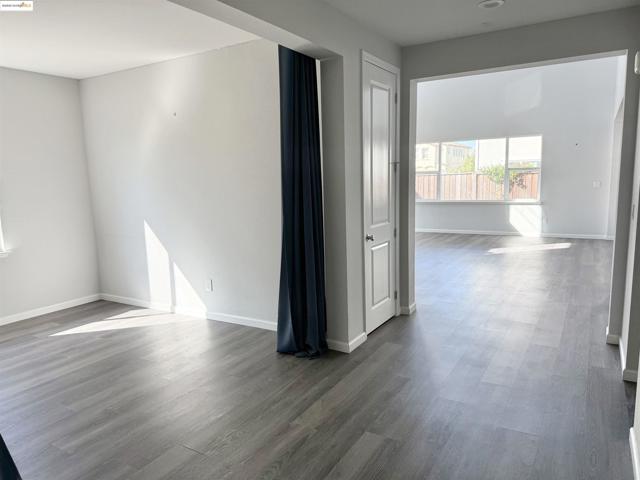 Empty room featuring dark wood-style flooring and baseboards