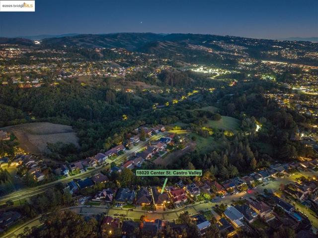 Aerial view at night of a residential view, view of wooded area, and a mountain view