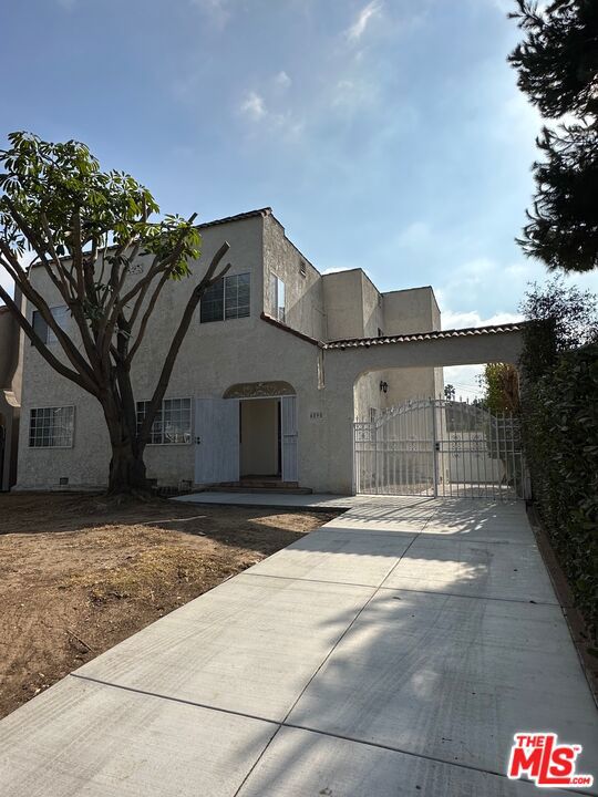 Ideally located near Larchmont Village, Hancock Park, and Koreatown, this beautifully updated Spanish-style home sits on a spacious lot in the historic Wilshire Park neighborhood. Featuring a gated driveway, the home welcomes you into a foyer with a grand wood staircase.  The light-filled living room with fireplace and ceiling fan flows into a large dining room, which opens to a modern kitchen with granite counters and new stainless steel appliances. Sliding doors lead to a covered patio and convenient laundry room with washer and dryer. A small bedroom and bathroom off the kitchen make for a perfect office or guest room.  Upstairs, there are two spacious bedrooms with walk-in closets, a stylish bathroom, and a generous primary suite with an en-suite shower. The detached garage and long driveway offer ample parking and storage. With a great walk score and easy freeway access, this home combines comfort, style, and convenience.