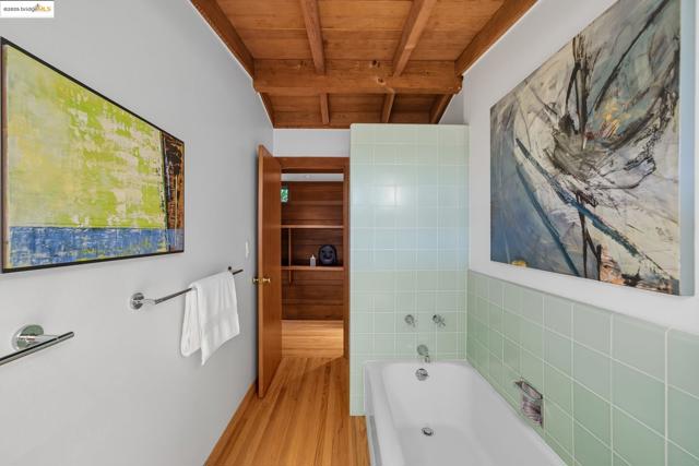 Bathroom featuring a bath, light wood-type flooring, and a wood ceiling with exposed beams