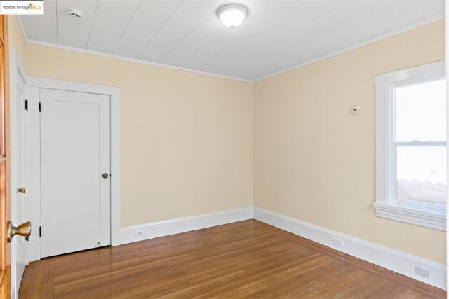 Unfurnished room with wood finished floors and ornamental molding