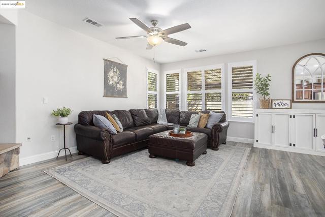 Living area featuring laminate wood-type flooring, healthy amount of natural light, and a ceiling fan