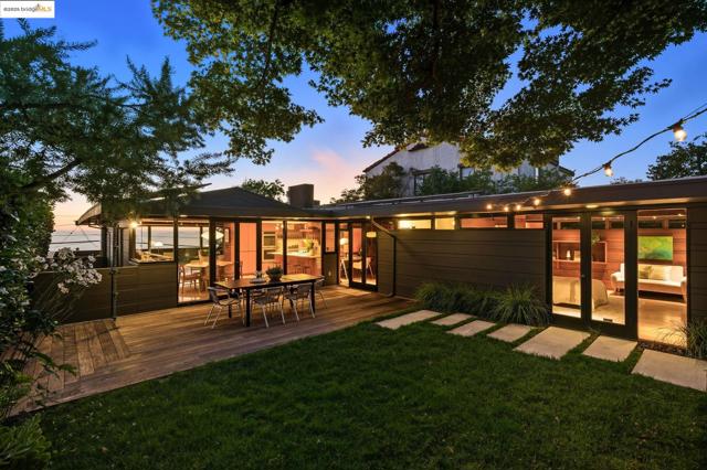 Back of property at dusk featuring a yard, a deck, and outdoor dining space