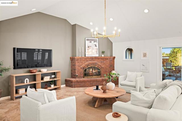 Living room with recessed lighting, a brick fireplace, lofted ceiling, and a chandelier