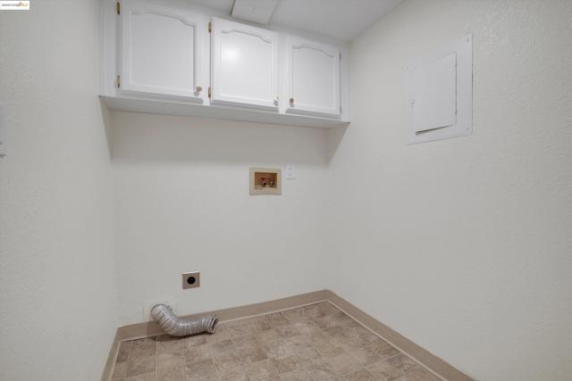 Laundry area with electric dryer hookup, cabinet space, electric panel, and hookup for a washing machine
