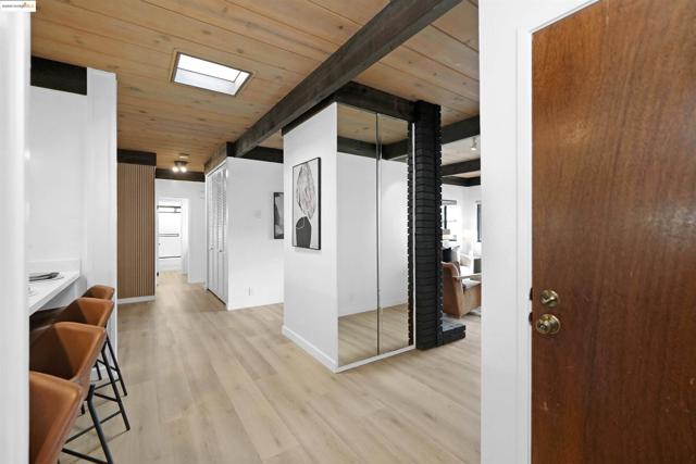 Hall with a wood ceiling with exposed beams and light wood finished floors