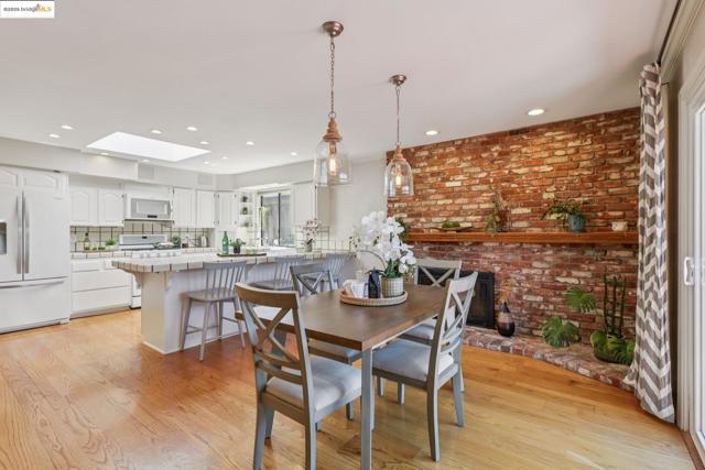 Dining space featuring a skylight, light wood finished floors, recessed lighting, and brick wall
