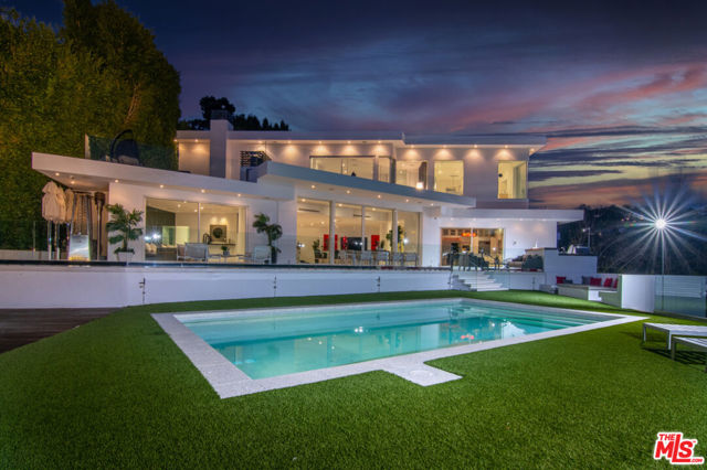 1247 Lago Vista Drive Beverly Hills, California Spectacular 4 BD, 5 BA ultra-modern view estate perched on over an acre in City of Beverly Hills! What more could you possibly want at this price? Perfect Trousdale alternative for those desiring breathtaking city to ocean views but also wanting more land and extreme privacy. This dazzling compound is fortressed with large steel gates at the entrance which open to an expansive tree-lined motor court that can accommodate up to 12 cars. Set far back from the street one enters through automatic glass doors into a home flooded with natural light, spacious open floorplan, and walls of glass. All rooms are perfectly oriented to take full advantage of the awe-inspiring views and bring the lush outdoor splendor in. The downstairs features living, dining, family and magnificent state-of-the-art kitchen all blending seamlessly with clean lines and sophistication. Motorized Fleetwood doors lead to an enormous flat backyard complete with heated saltwater pool, sprawling decks, patios, grassy area, built-in BBQ, and fire pit. Walk a bit further and you will discover endless pathways leading to your own flourishing hillside orchard filled with mature lemon, lime, orange, and avocado trees. The second level includes an elegant, curved staircase that leads to the upstairs bedrooms including a huge primary suite complete with fireplace, private deck, generous walk-in closets, and luxurious spa-like bathroom. Meticulous attention to detail and top-of-the-line materials and finishes throughout. Additional amenities include solar energy for electric and pool, advanced Lutron lighting/shade system and Creston Home Smart Integration. Property also comes with the ability to build a 1200 sf ADU without planning commission approval that can add 2 bedrooms and an expanded garage should the buyer desire more space. Seller previously initiated process. This exceptional entertainer's estate located on a street-to-street lot in Beverly Hills proper is a must see and offers incredible value for any buyer! Even better - no mansion tax down the line! A unique and very special opportunity not to be missed!