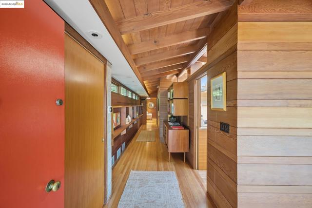 Hallway with wood walls, light wood-style floors, and wooden ceiling