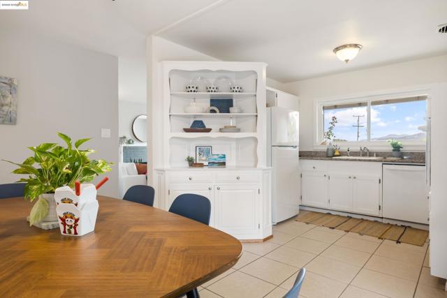 Kitchen with white cabinetry, open shelves, white appliances, light tile patterned flooring, and dark stone counters