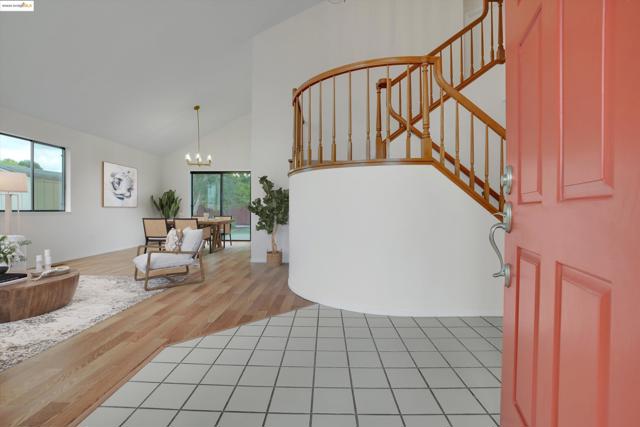 Entrance foyer featuring healthy amount of natural light, high vaulted ceiling, a chandelier, light wood-style flooring, and stairway