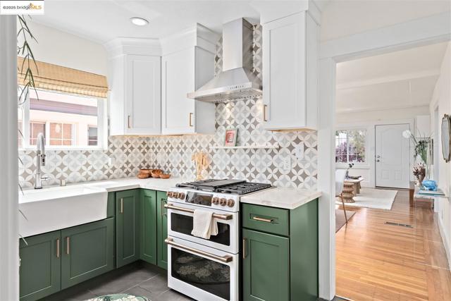 Kitchen featuring green cabinetry, decorative backsplash, double oven range, and white cabinetry