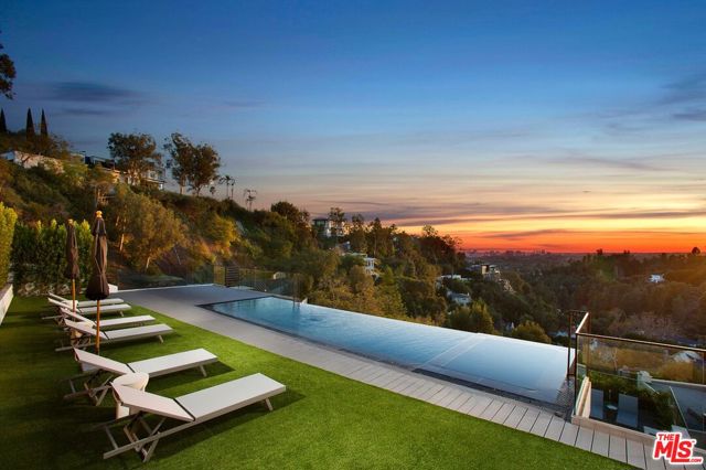 Located in Beverly Hills, this modern masterpiece is awaiting for you. Be prepared to be amazed by this incredible home. This property is a real entertainer's delight with a two-story rooftop deck enveloped by mind-blowing views & featuring a fully equipped kitchen with BBQ, ample patio space & a stunning infinity pool that blends into the views. Additional home features include media lounging with bar, well-appointed guest suites, smart windows, expansive garage, laundry room & more!!