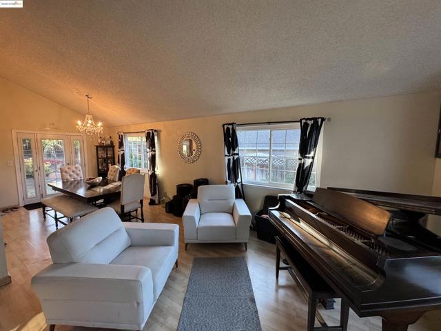 Living room featuring vaulted ceiling, a chandelier, wood finished floors, and a textured ceiling