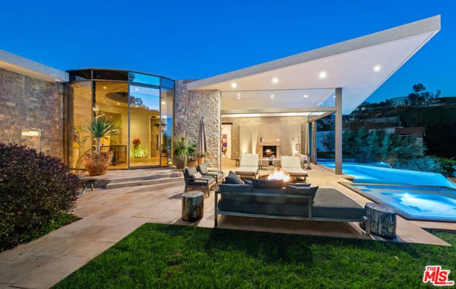 9233 Swallow Drive Los Angeles, California Embodying an organically modern aesthetic with its stone and glass facade, 9233 Swallow Drive takes up prominent residence in the highly coveted Bird Streets. Designed by the acclaimed Bradley Bayou, this five-bedroom, eight-bath masterpiece spans 7,308 square feet and offers tranquility above the bustling Sunset Strip. The open chef's kitchen, with Miele appliances and wood and stone accents, seamlessly integrates with a living/dining area bound by a dramatic two-sided gas fireplace. This space epitomizes the indoor/outdoor California lifestyle, with glass walls welcoming you into a harmonious exterior with panoramic city views. An ivy-covered facade and exquisite landscaping offer a verdant oasis, and among the fire pits, fireplace, multiple patios, and ample space for entertaining is the crown jewel: the infinity swimming pool with spa. More sanctuary awaits in the primary suite, with a fireplace, dual walk-in closets, and sliding glass doors that open to a private Zen garden and yoga deck. Indulge yourself with the ensuite bathroom's dual floating vanities, sunken tub, and marble steam shower, all accentuated by cool limestone flooring. The remaining four bedrooms are also ensuite, each with custom materials and elements for added distinction.Other amenities include a wet bar, library, gym, office, lounge, wine cellar, and four-car garage. A show-stopping feature is a luxe screening room with scarlet hues inspired by Radio City Music Hall. There's also a winding staircase and glass elevator for added touches of elegance, and smart-home technology to ensure 21st-century living at its finest. Nestled against the Hollywood Hills and on a corner lot, this home exists mere minutes from some of the best shopping, dining, and entertainment, but you'll love returning to this architectural treasure time and again.
