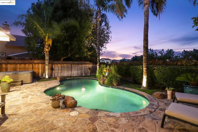 Pool at dusk featuring a hot tub, a fenced backyard, and a patio area