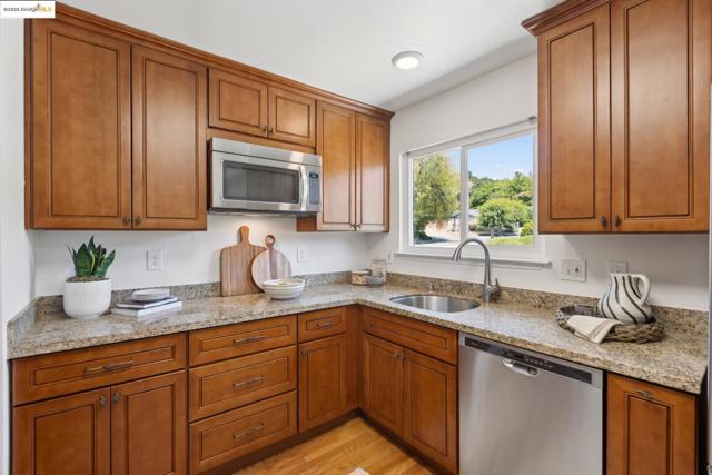 Kitchen featuring appliances with stainless steel finishes, brown cabinetry, and light wood-type flooring
