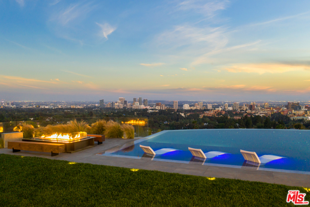 AUCTION: Bid April 21-26. Currently Listed for $87,777,777. Reserve $50M. Representative Onsite Daily.From the San Gabriel Mountains to the Channel Islands, the most scenic views of Los Angeles are yours to discover from this Bel Air architectural masterpiece. Perched atop a promontory, the main entrance dazzles with its floating marble bridge-like pathway leading you to the opulent front door that soars high above. The living room offers sleek style with no shortage of luxury finishes: a retractable hydraulic DJ table for top-tier entertainment compliments the gleaming glass elevator and its encompassing Feng Shui koi pond. Incomparable luxury awaits in the primary suite, where a towering glass wall opens to a floating wrap-around deck composed of marble and glass, with all of Los Angeles beyond. The atmosphere is reminiscent of a seven-star resort, and extends to the en suite bath, where dual-facing showers, marble vanities, and expansive walk-in closets surround the show-stopping soaking spa tub. Venture outdoors to relax by the oversized infinity-edge pool with panoramic views of L.A. With its dramatic views of Los Angeles forever protected by a property easement, you can redefine elegance and luxury from the clouds themselves, high above the City of Angels.