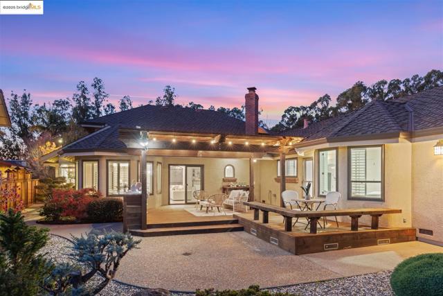 Back of property at dusk with a chimney, a deck, stucco siding, crawl space, and a pergola