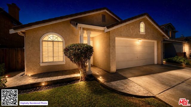 Single-story stucco home at night with an attached garage, arched windows, and a warmly lit entry.