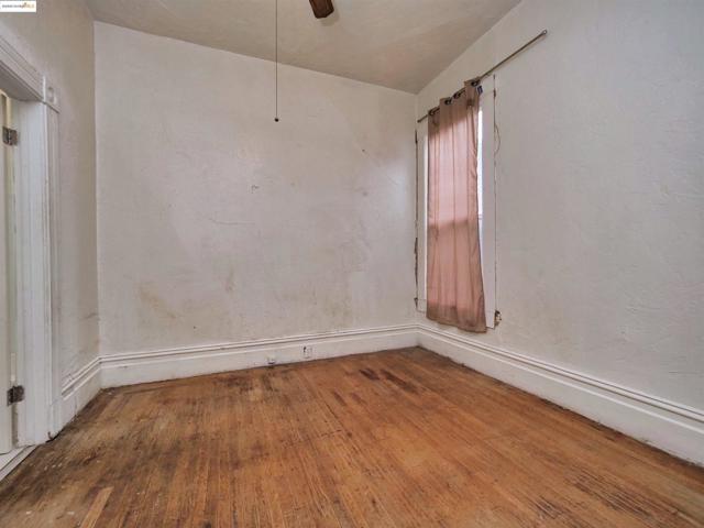 Unfurnished room featuring hardwood / wood-style floors, ceiling fan, and a textured wall