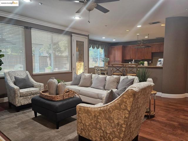 Living area with dark wood-type flooring, recessed lighting, crown molding, and ceiling fan