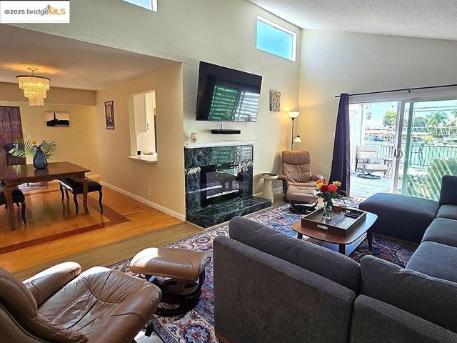 Living area with high vaulted ceiling, wood finished floors, a textured ceiling, and a fireplace